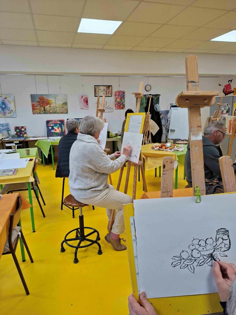 Des adultes dessinent une nature morte à un chevalet dans un atelier collectif